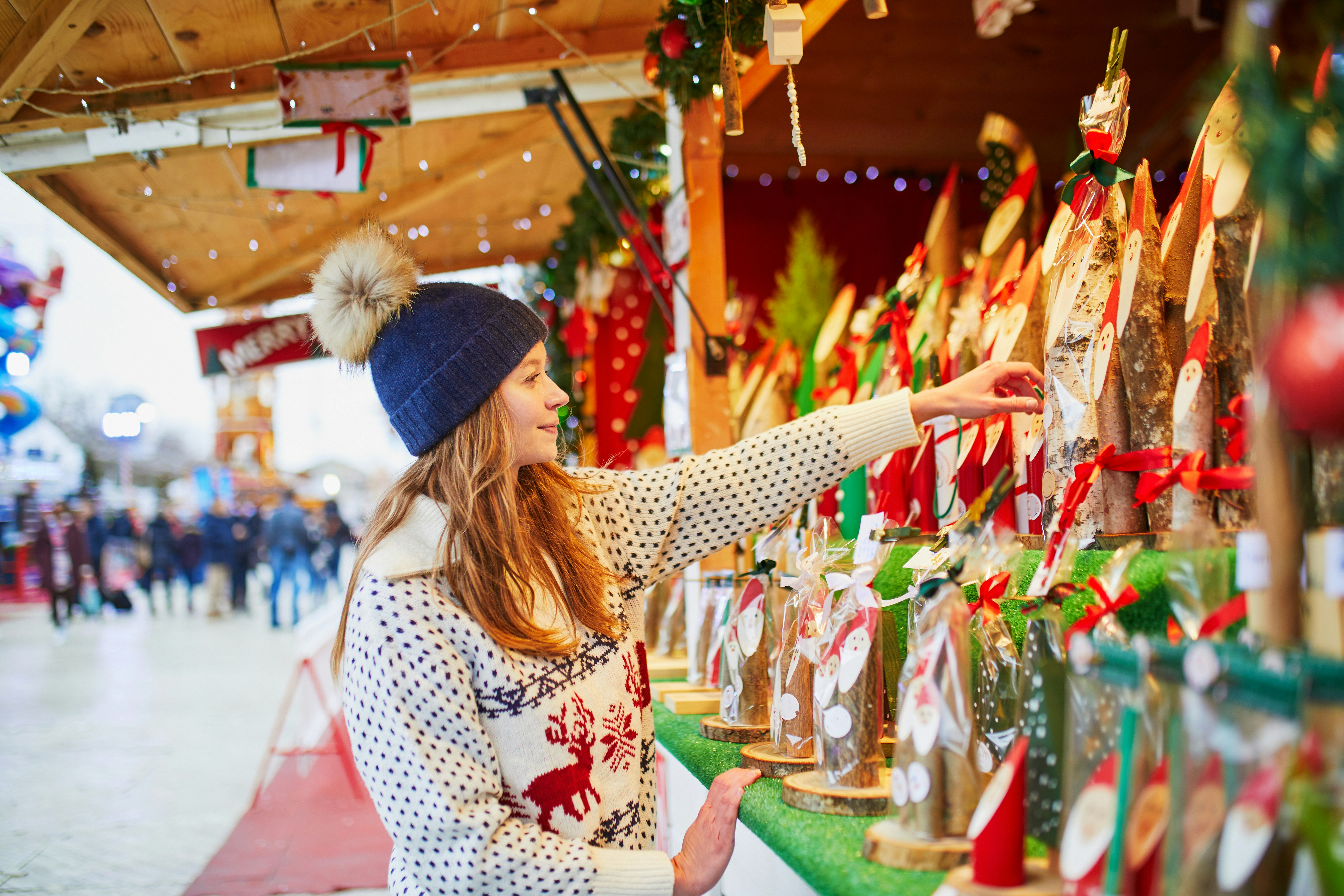 Woman browsing festive decorations at Paris Christmas market stall.