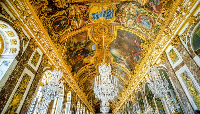 Hall of Mirrors ceiling artwork at Palace of Versailles, France, showcasing intricate historical designs.
