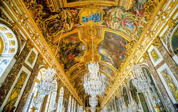 Hall of Mirrors ceiling artwork at Palace of Versailles, featuring intricate paintings and chandeliers.
