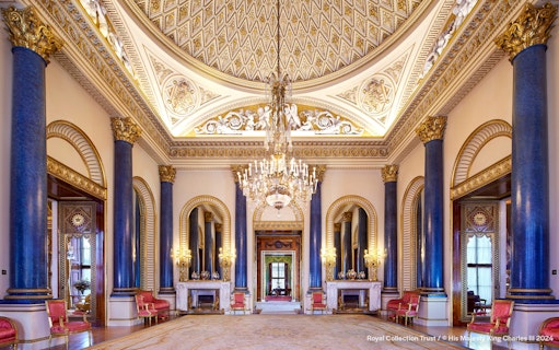 Music Room at Buckingham Palace with ornate ceiling, chandeliers, and blue columns.