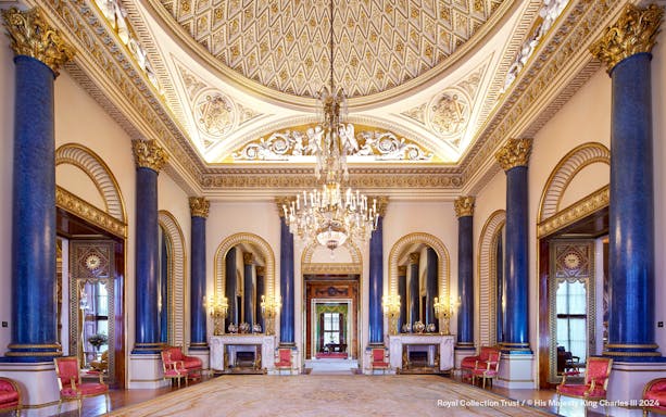 Music Room at Buckingham Palace with ornate ceiling, chandeliers, and blue columns.