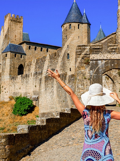Visitor exploring Carcassonne Castle's historic stone walls in France.