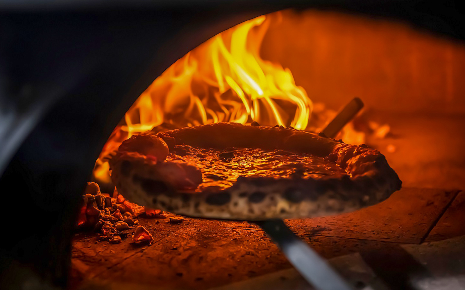 People making pizza in a Florence cooking class, with hands kneading dough and adding toppings.