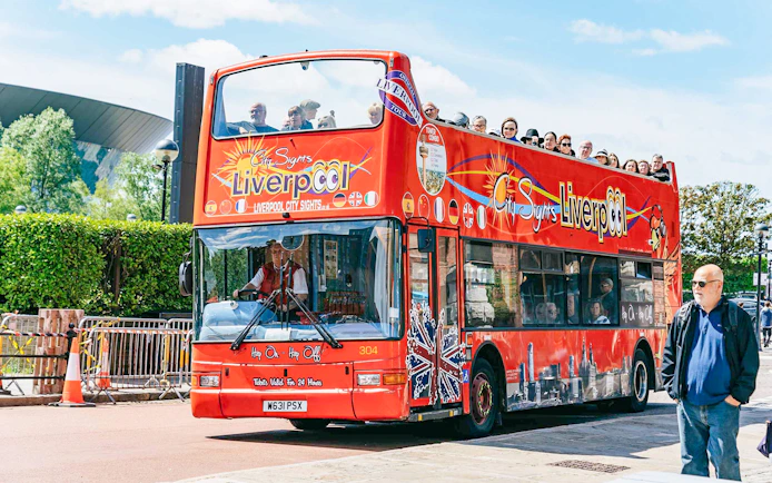 Liverpool hop on hop off bus with tourists on upper deck.