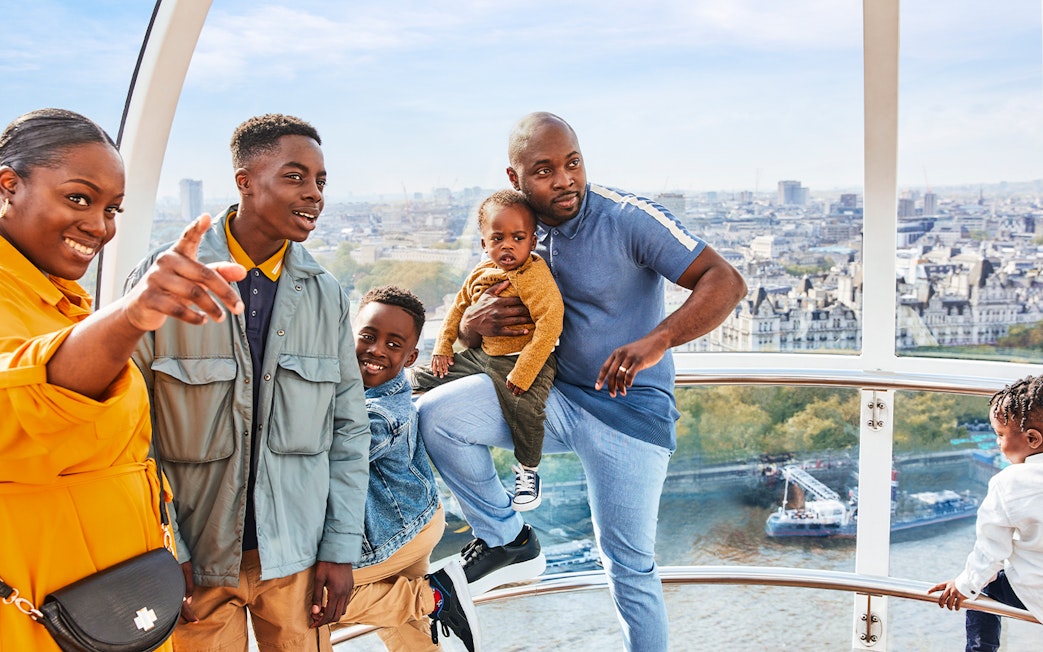 Family enjoying view from London Eye capsule, cityscape and Thames River visible.