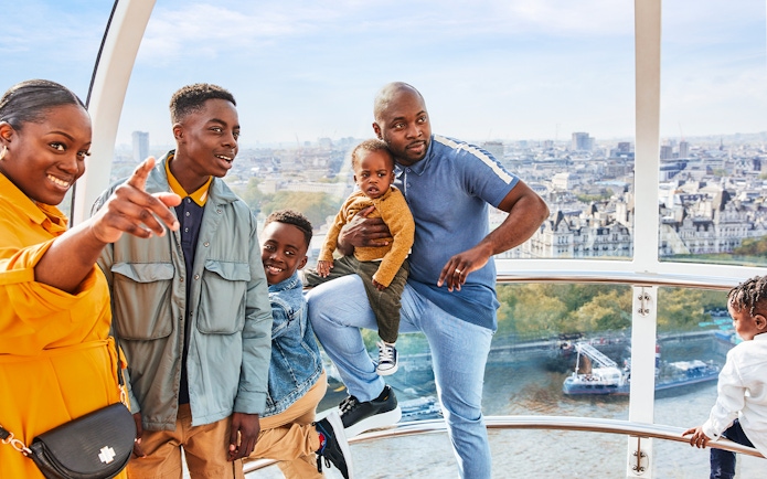 Family enjoying view from London Eye capsule, cityscape and Thames River visible.