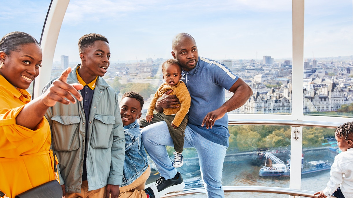 Family enjoying view from London Eye capsule, cityscape and Thames River visible.