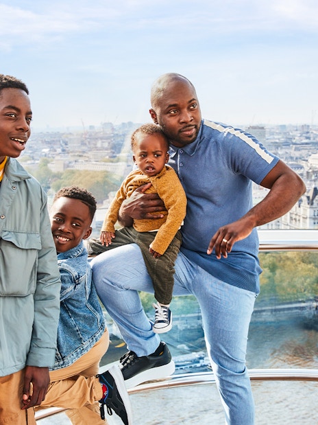Family enjoying view from London Eye capsule, cityscape and Thames River visible.