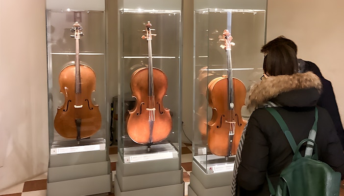 Cellos on display at Accademia Gallery, Florence, viewed by visitors.