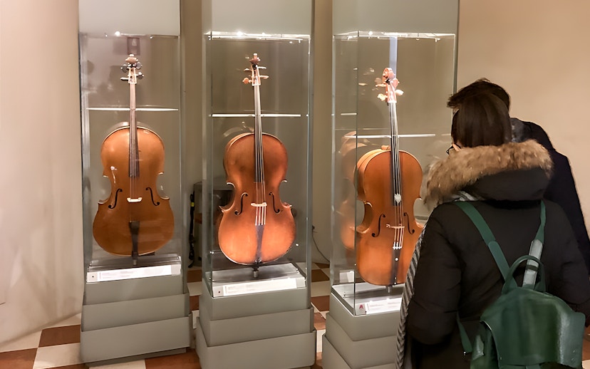 Cellos on display at Accademia Gallery, Florence, viewed by visitors.