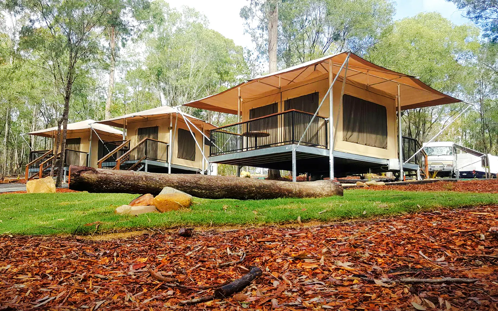 Glamping tents at Paradise Country Farmstay surrounded by trees and natural landscape.