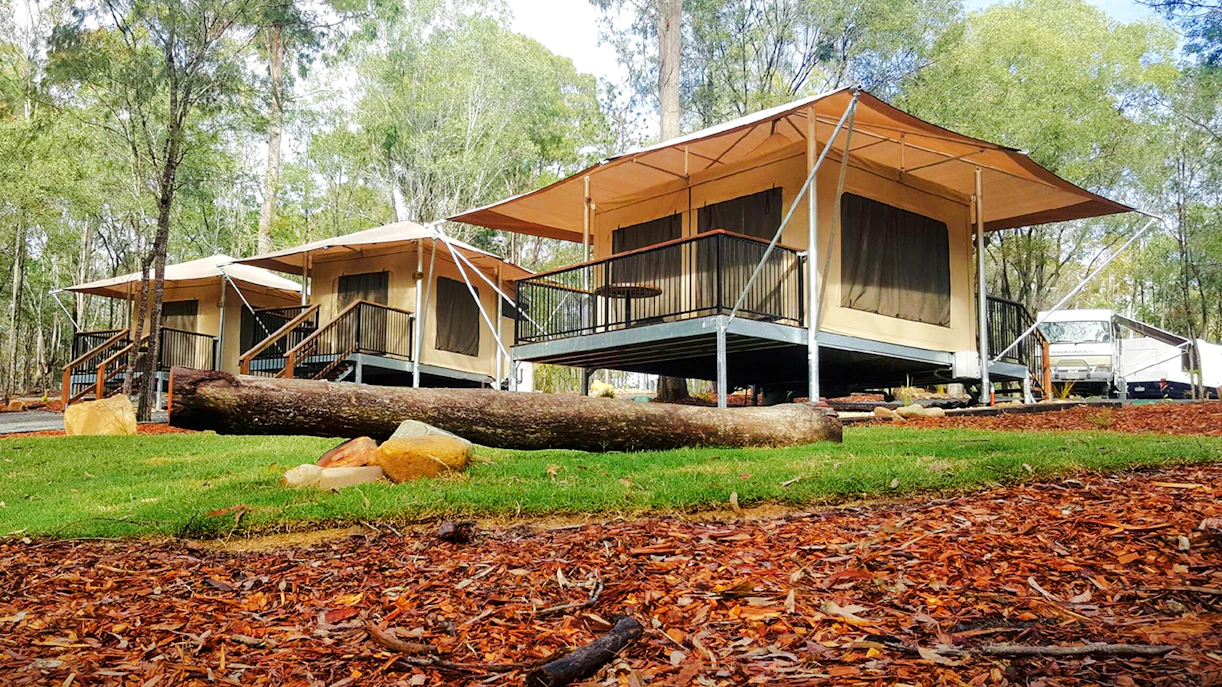 Glamping tents at Paradise Country Farmstay surrounded by trees and natural landscape.