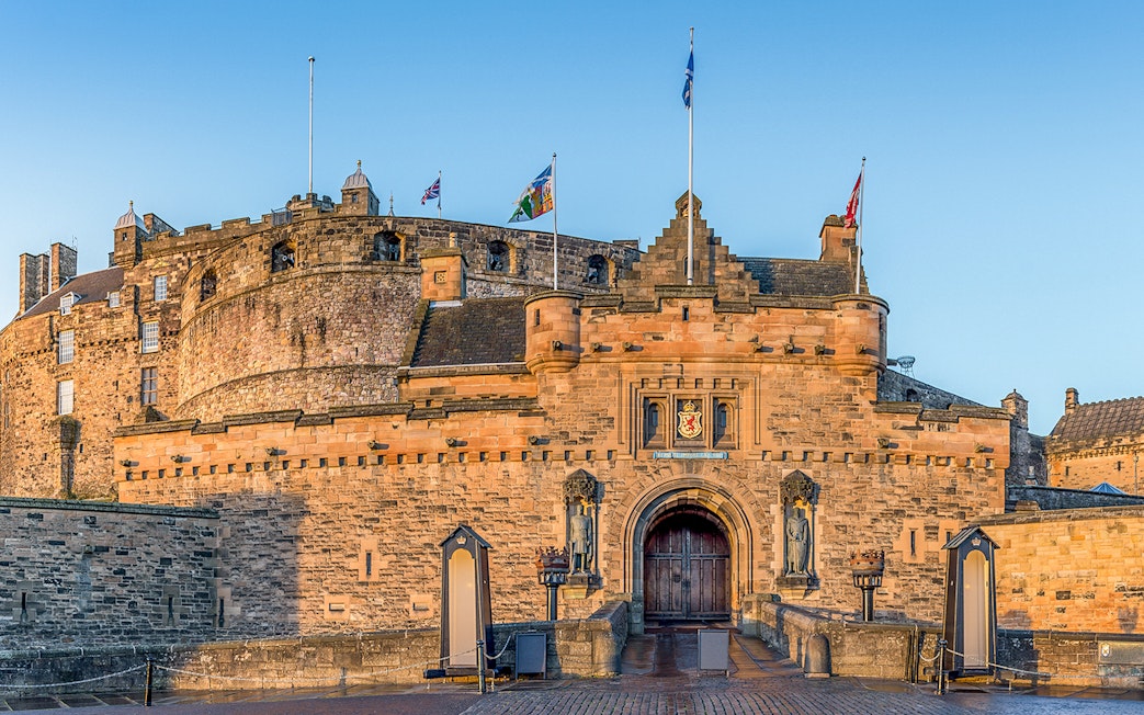Edinburgh Castle front gate with stone walls and flags flying above.