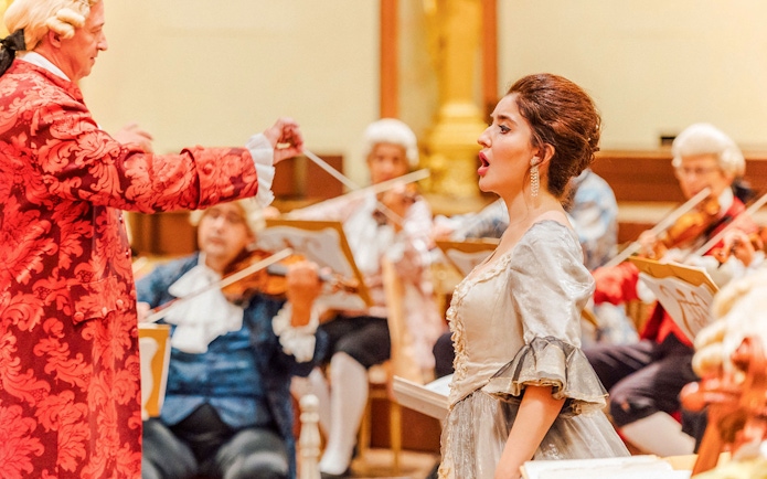 Mozart Orchestra performing in Vienna's Golden Hall with a singer in period costume.