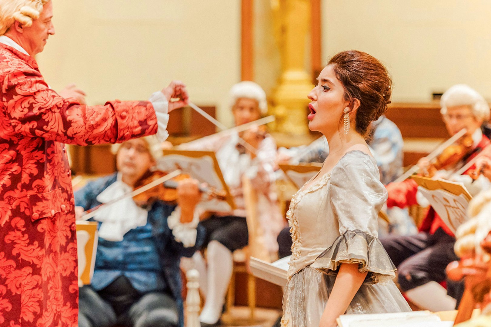 Mozart Orchestra performing in Vienna's Golden Hall with a singer in period costume.