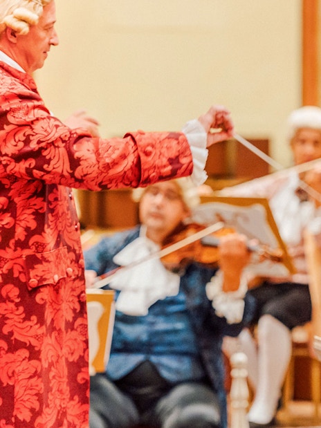 Mozart Orchestra performing in Vienna's Golden Hall with a singer in period costume.