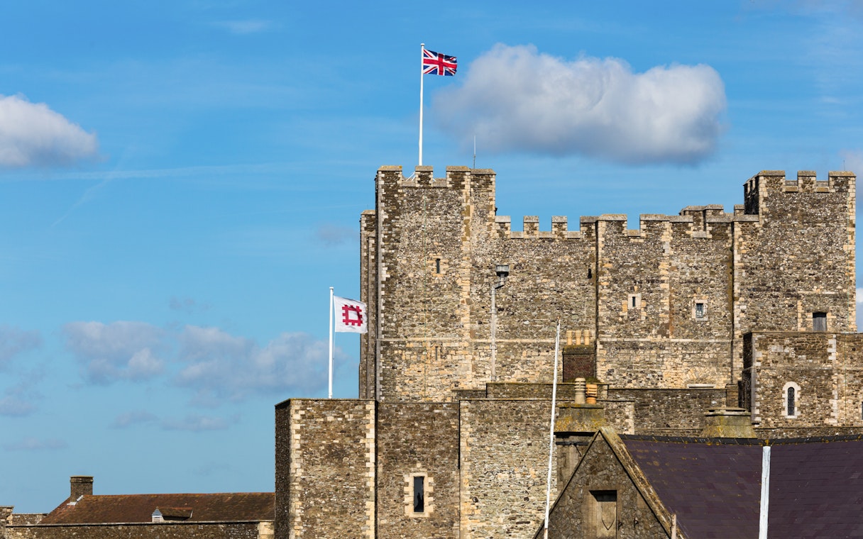 Dover Castle with Union Jack flag on a sunny day, part of Canterbury and Dover tour.