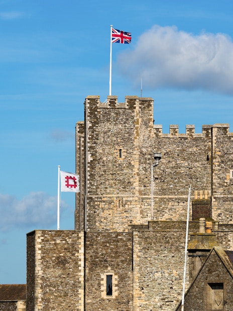 Dover Castle with Union Jack flag on a sunny day, part of Canterbury and Dover tour.