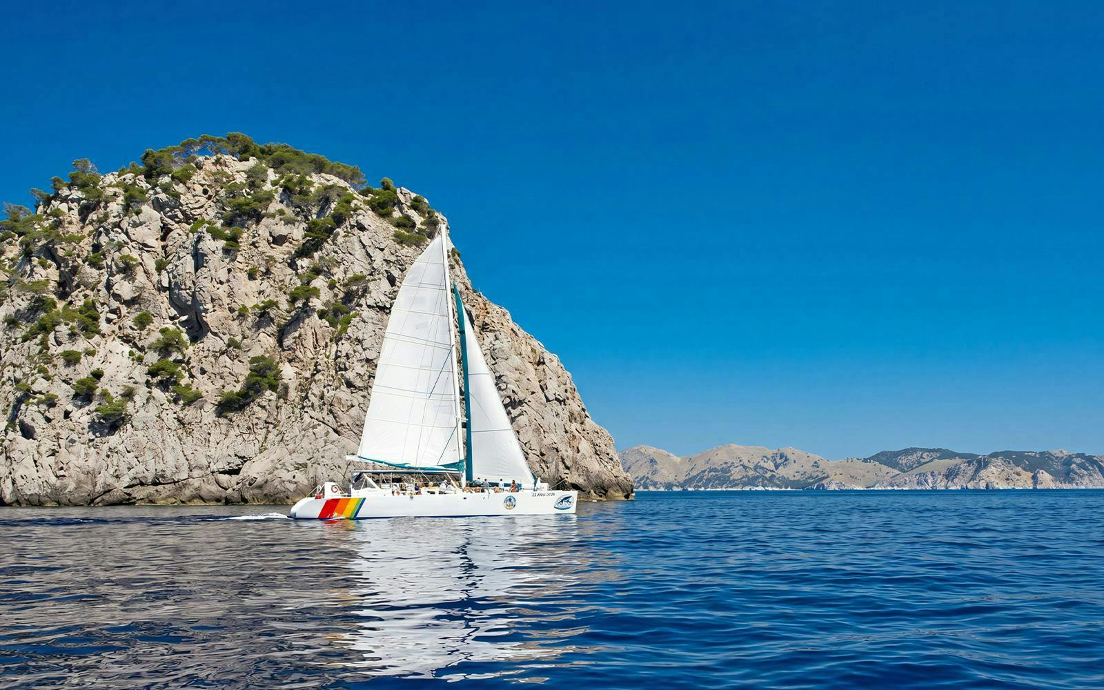 Catamaran sailing near rocky cliffs at Portals Vells, Mallorca.