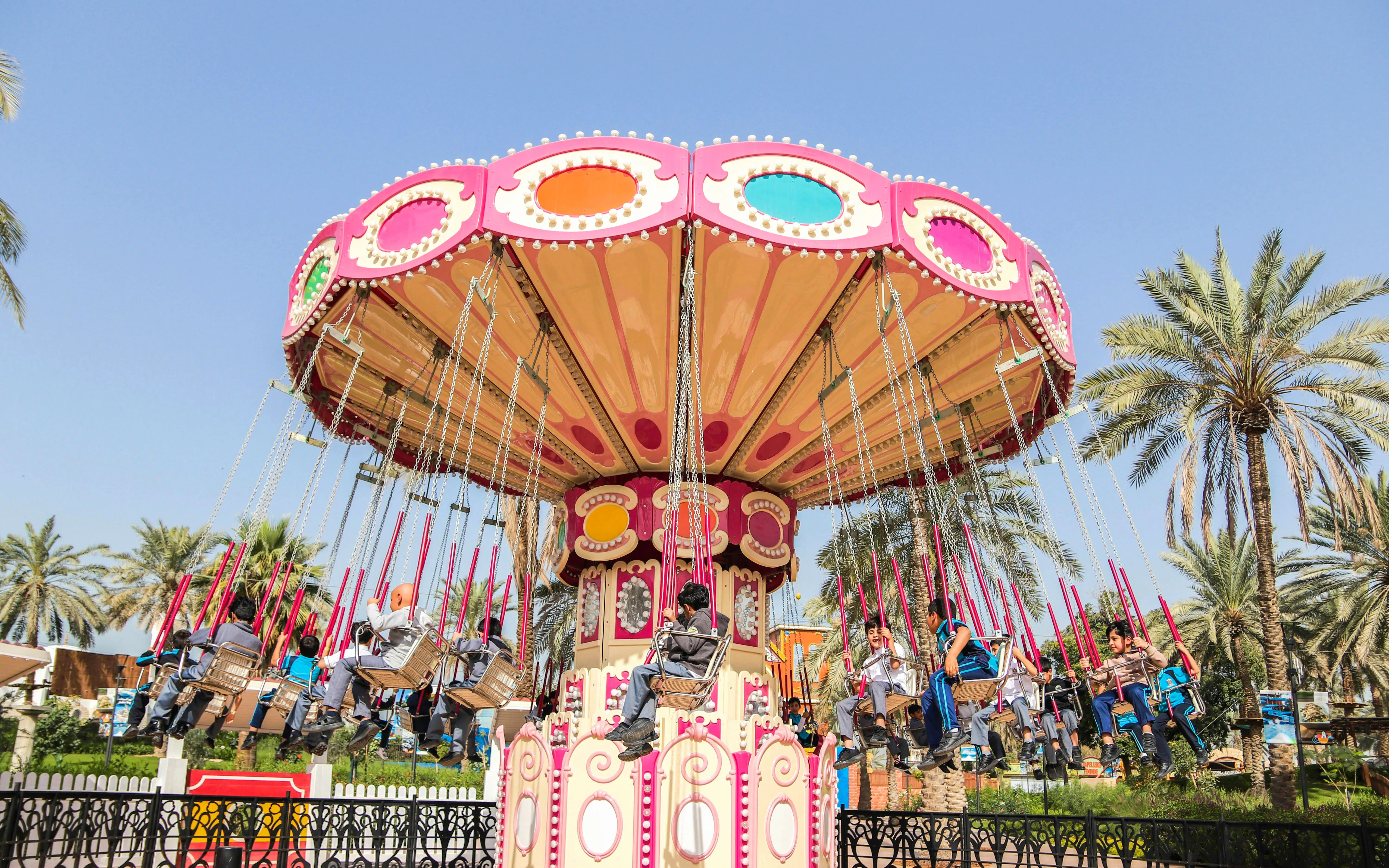 Swing ride at Al Montazah Parks, Island of Legends, with people enjoying the attraction.