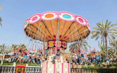 Swing ride at Al Montazah Parks, Island of Legends, with people enjoying the attraction.