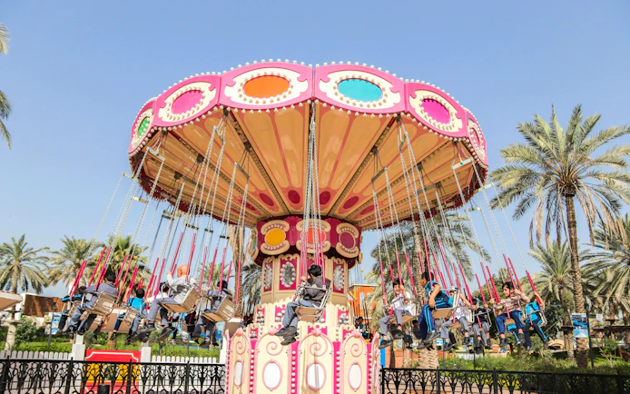 Swing ride at Al Montazah Parks, Island of Legends, with people enjoying the attraction.