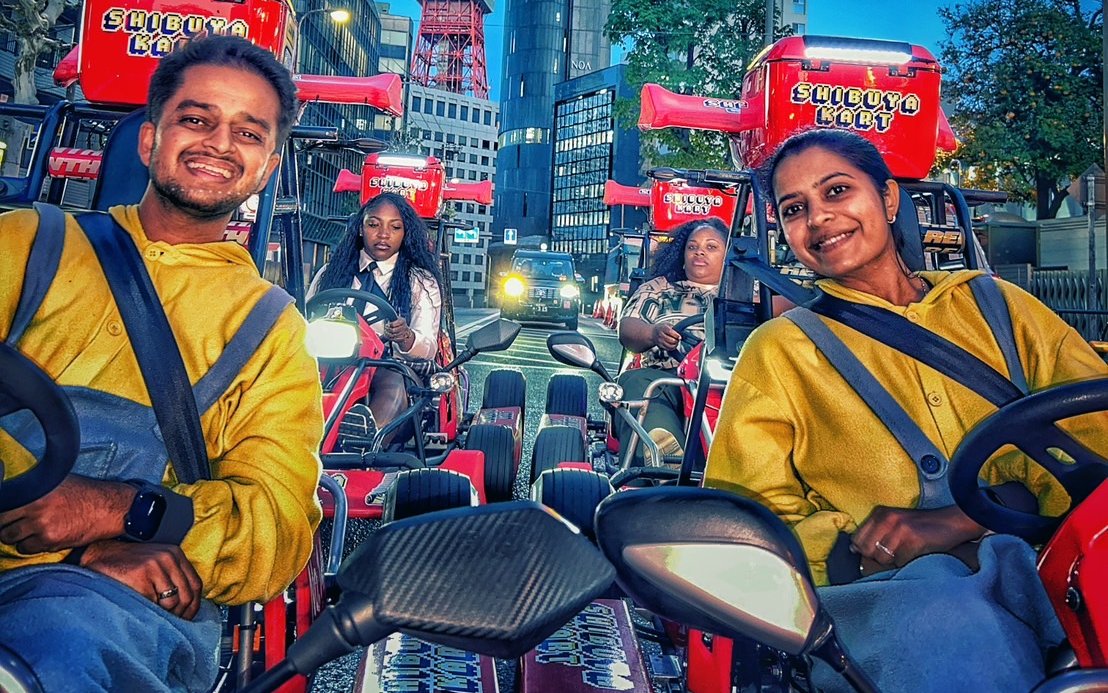 Go-karting tour participants driving through Shibuya, Tokyo with cityscape backdrop.