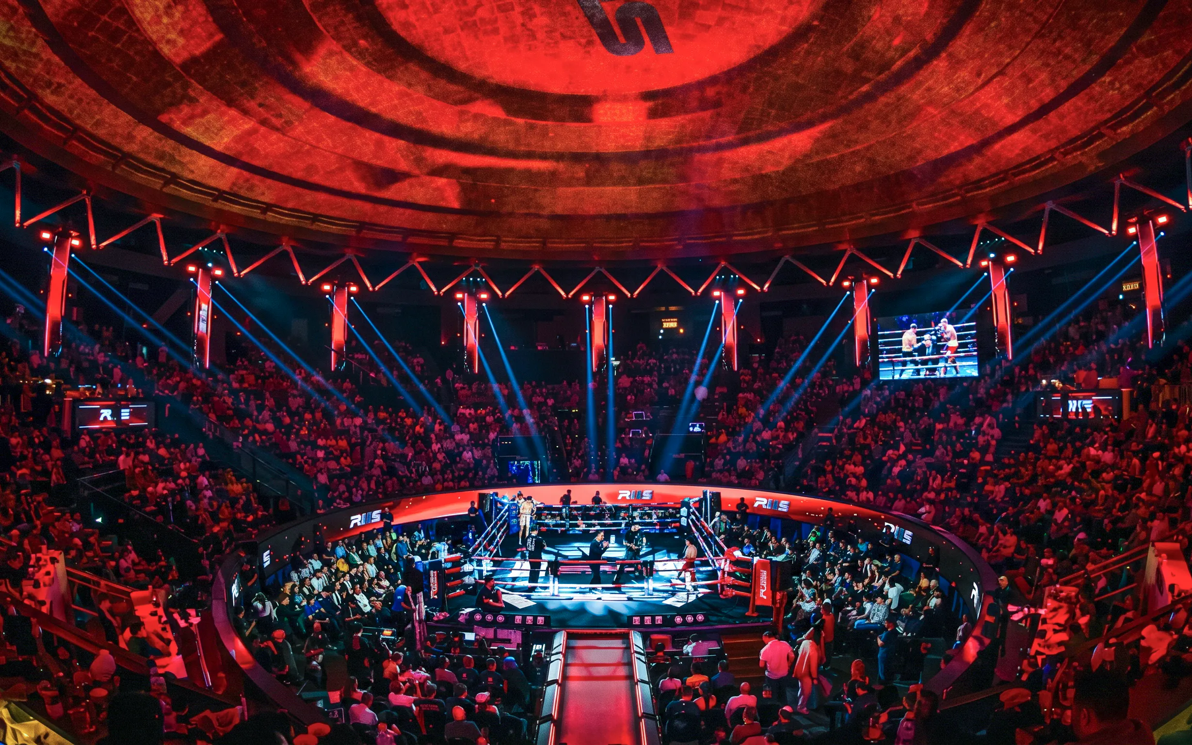 Muay Thai match at Rajadamnern Stadium, Bangkok, with a vibrant crowd and illuminated arena.