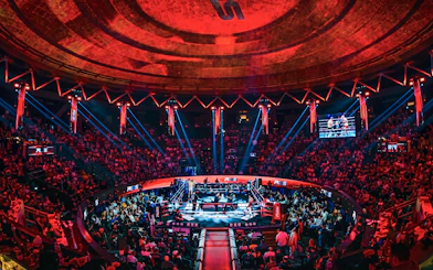 Muay Thai match at Rajadamnern Stadium, Bangkok, with a vibrant crowd and illuminated arena.