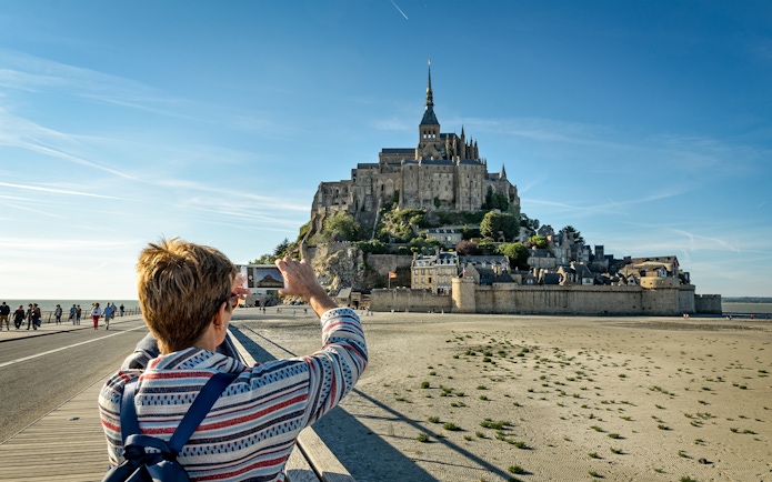 Tourist photographing Mont Saint Michel in Normandy, France.