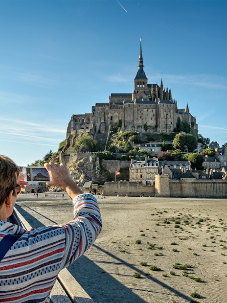 Tourist photographing Mont Saint Michel in Normandy, France.