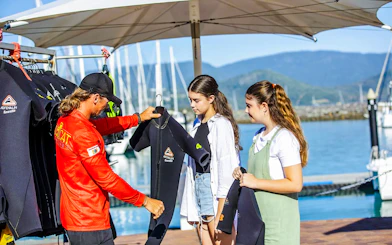 Tour guide handing wetsuits to participants on Thundercat Whitsundays Full Day Tour at marina.