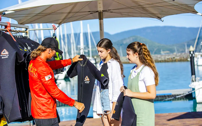 Tour guide handing wetsuits to participants on Thundercat Whitsundays Full Day Tour at marina.