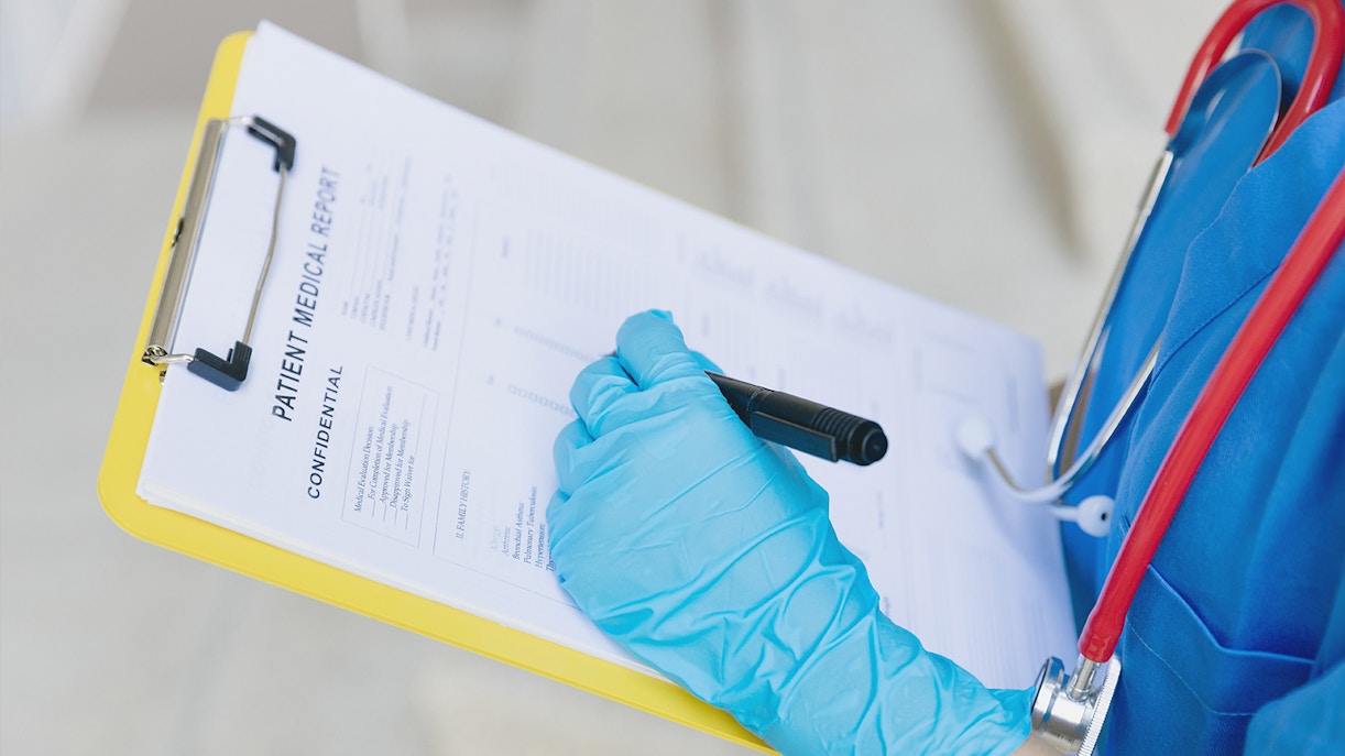 Nurse writing follow-up information on medical report in hospital.