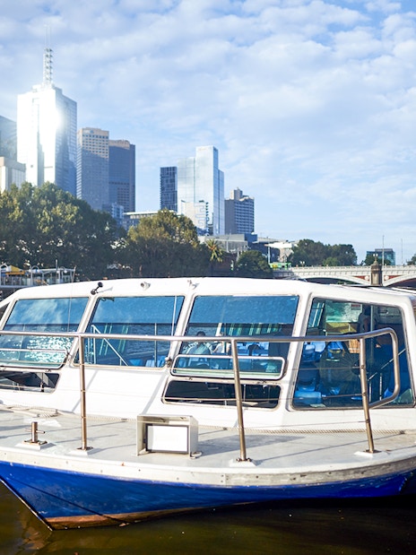 Melbourne River Cruise boat docked with city skyline in the background.