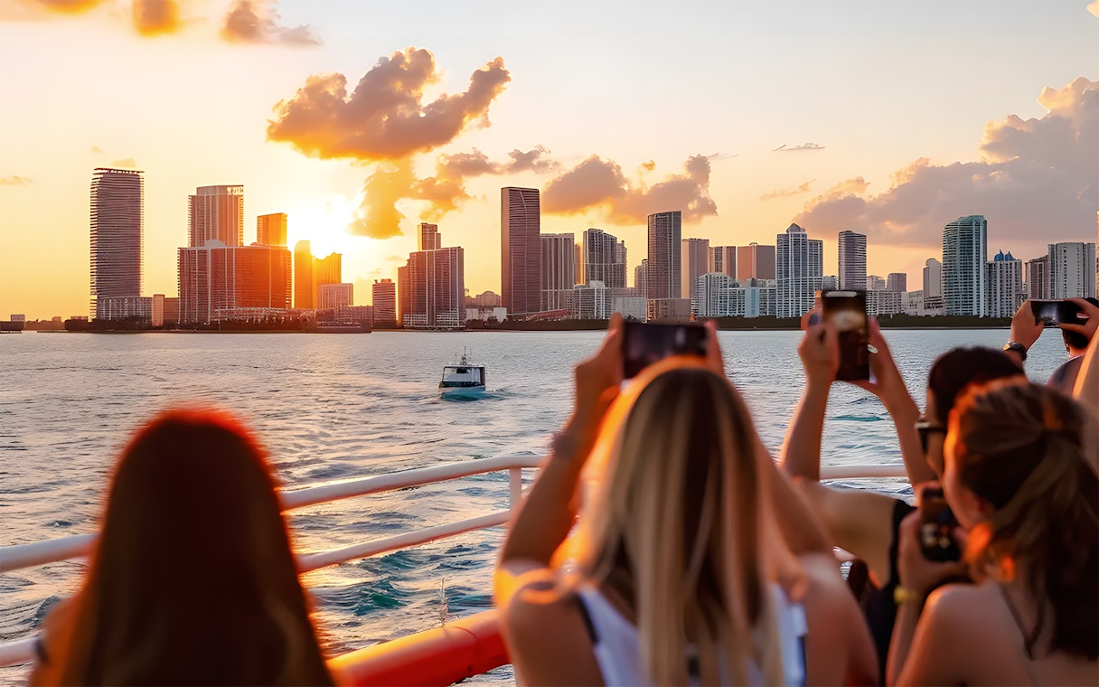 Guests photographing Miami skyline from a cruise at sunset.