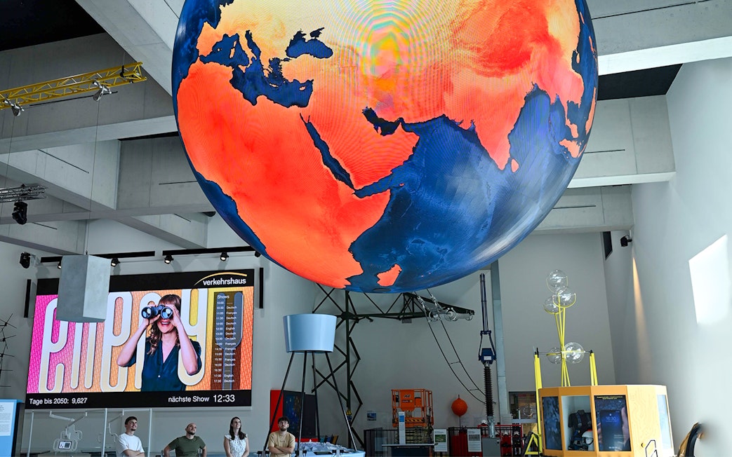 Giant globe display at Swiss Museum of Transport in Lucerne with visitors observing.