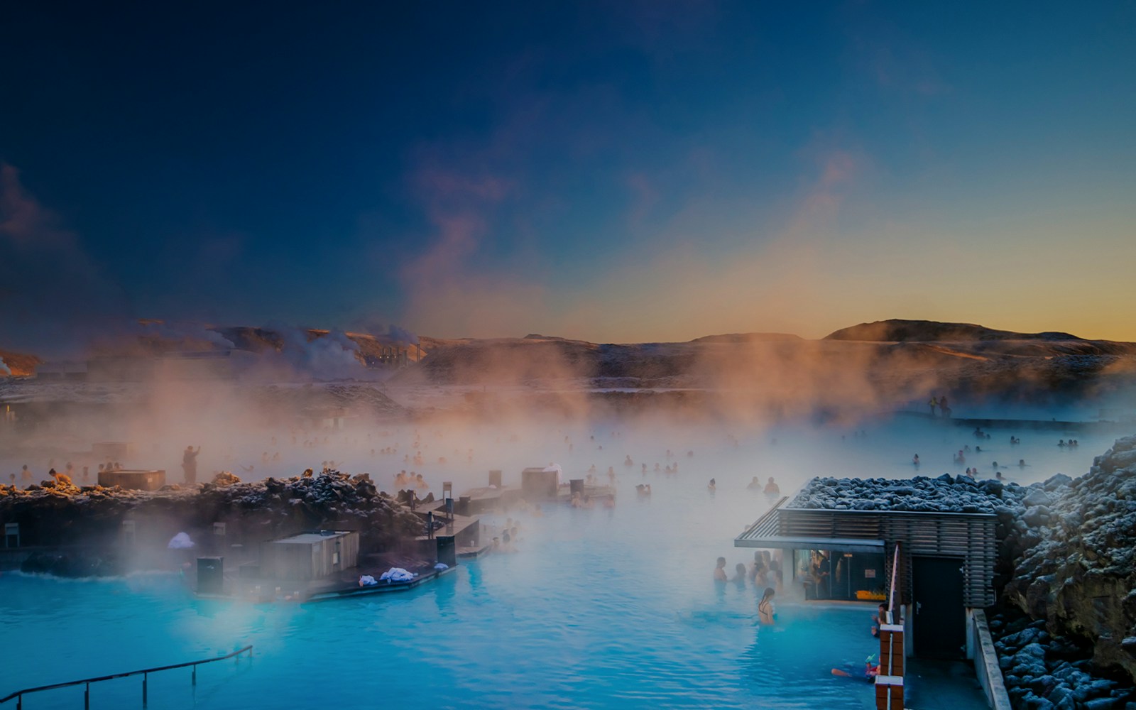 Tourists relaxing in Blue Lagoon hot spring spa, surrounded by Iceland's volcanic landscape.