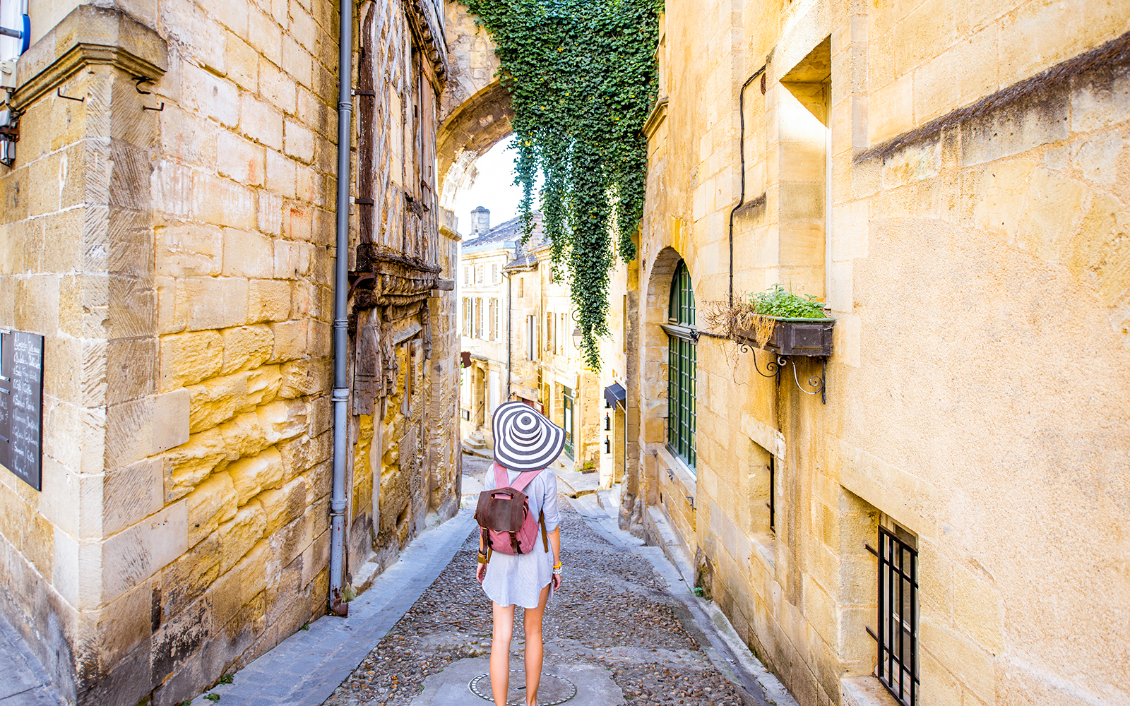 Person walking down a narrow cobblestone street in Saint Emilion, France.