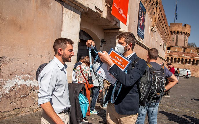 Visitors at Castel Sant'Angelo entrance in Rome, holding tickets and lanyards.
