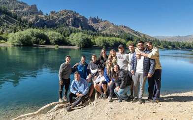 Tour group by a lake with mountain backdrop in Patagonia.