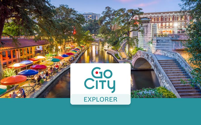 San Antonio River Walk with colorful umbrellas and stone bridge, Go City Explorer Pass.
