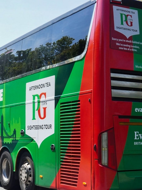 Afternoon Tea Bus with PG Tips branding on a scenic London road.