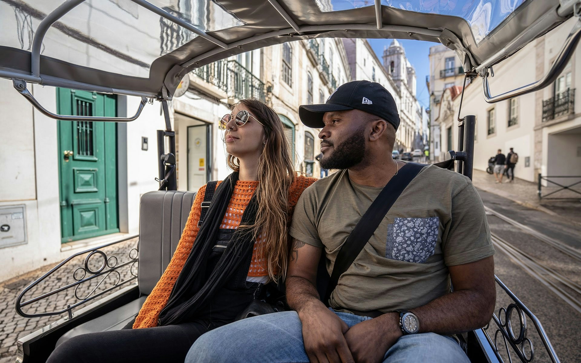 Tourists in a tuk-tuk exploring a street in Lisbon.