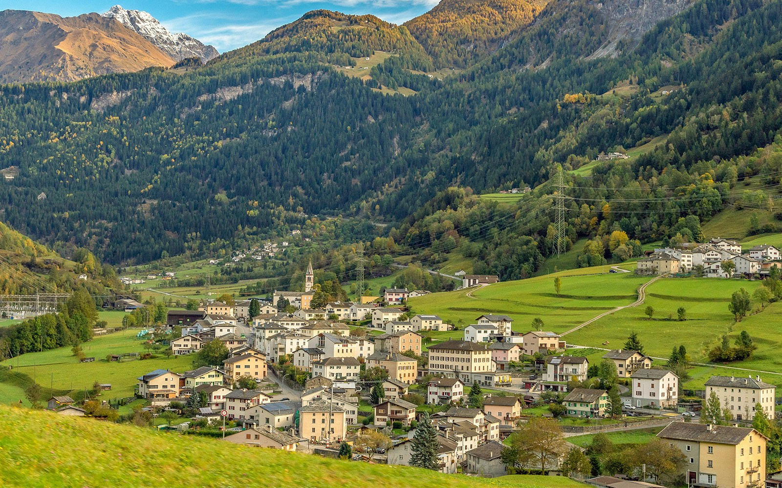 Swiss alpine lake in the mountains, Poschiavo (Miralago), Switzerland. Bernina massive peaks in the background of the green valley, blue sky with clouds