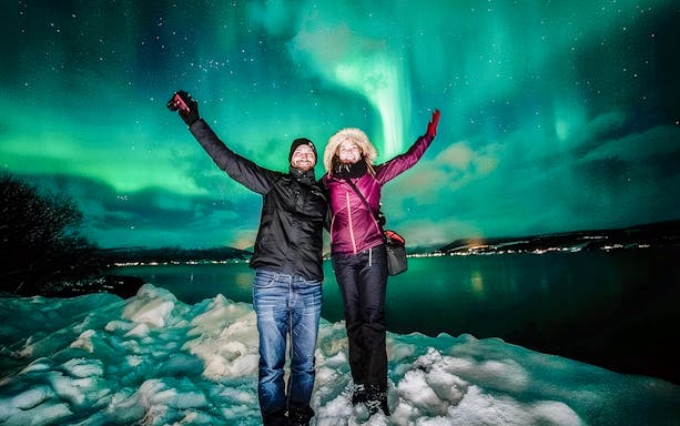 Guests on Northern Lights tour in Tromsø, Norway, with aurora borealis in the sky.