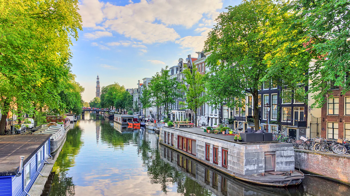 Houseboats along Prinsengracht canal in Amsterdam with Westerkerk in the background.