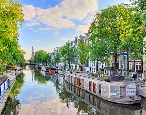Houseboats along Prinsengracht canal in Amsterdam with Westerkerk in the background.