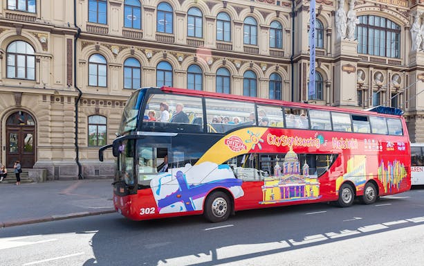 Helsinki sightseeing bus in front of historic building on hop-on hop-off tour.