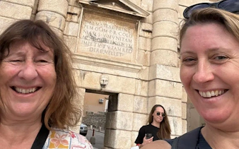 Two people smiling in front of the Land Gate in Zadar during a self-guided city exploration game.